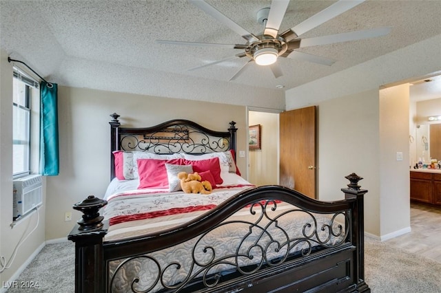 bedroom with a textured ceiling, light colored carpet, ceiling fan, cooling unit, and connected bathroom