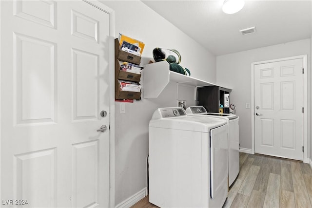 washroom featuring laundry area, visible vents, baseboards, light wood-style floors, and washer and clothes dryer