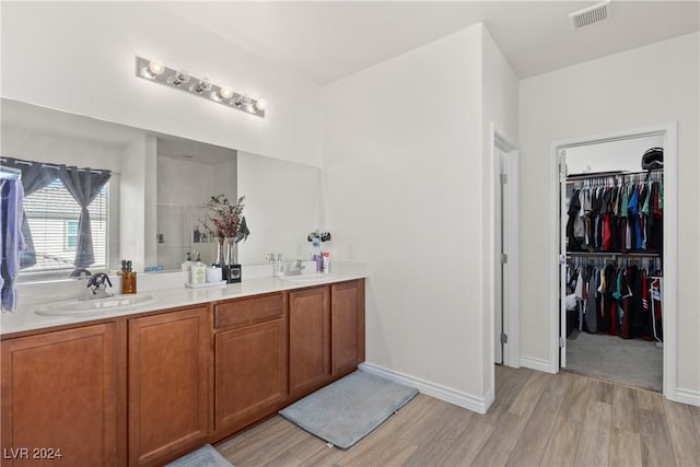 bathroom featuring double vanity, visible vents, a sink, and wood finished floors