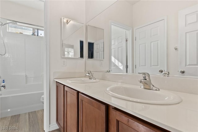 bathroom featuring double vanity, a sink, toilet, and wood finished floors