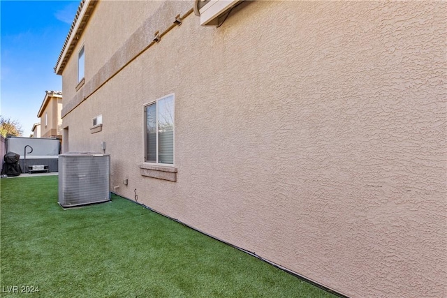 view of home's exterior featuring stucco siding, a lawn, and central AC unit