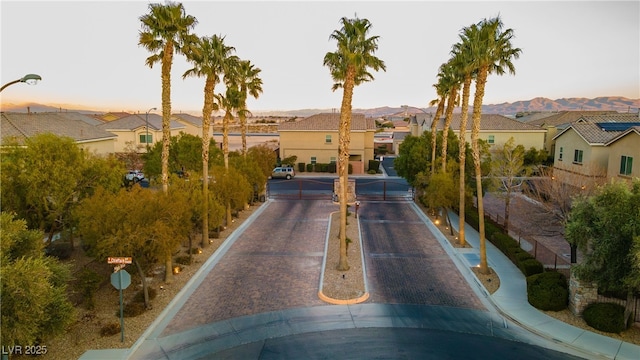 view of street with curbs, a gated entry, traffic signs, and a residential view