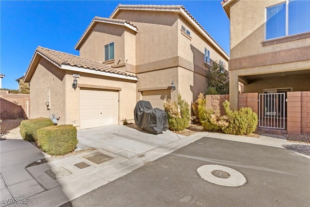 view of front of home featuring a garage, a tiled roof, concrete driveway, and stucco siding