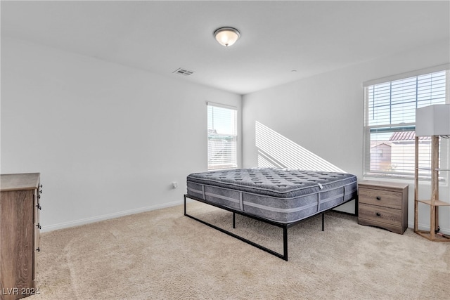 bedroom with light colored carpet and multiple windows