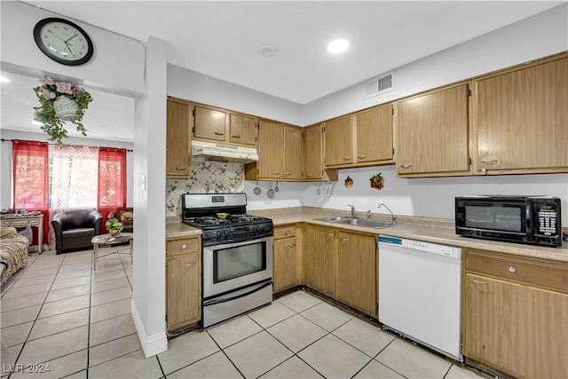 kitchen with white dishwasher, sink, gas range, decorative backsplash, and light tile patterned flooring