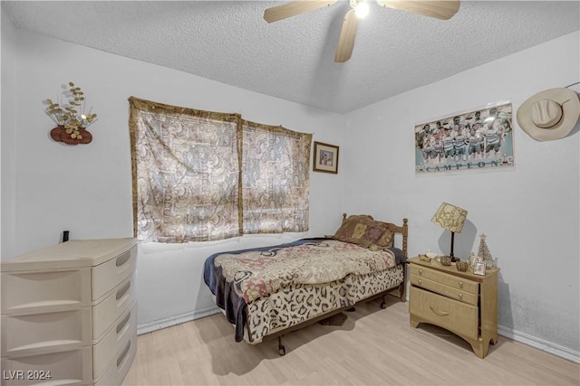 bedroom featuring ceiling fan, light hardwood / wood-style floors, and a textured ceiling