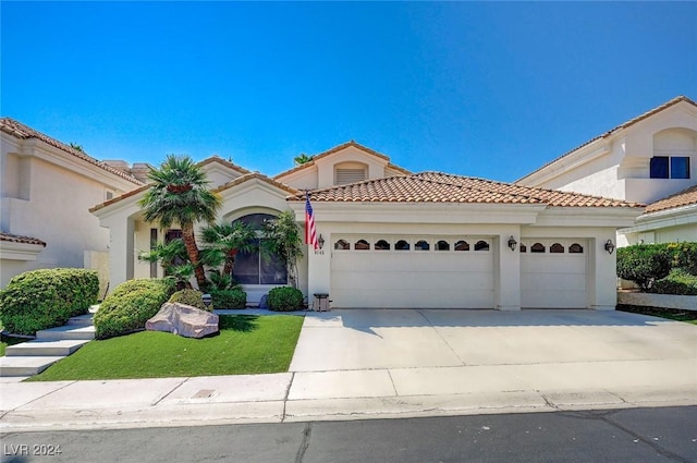 mediterranean / spanish home with a garage and a front lawn