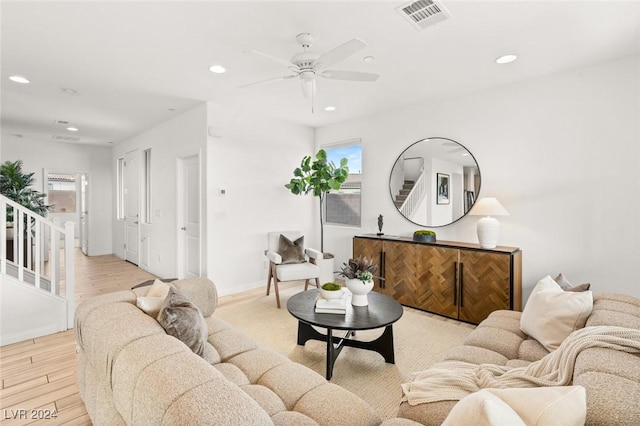 living room featuring light hardwood / wood-style floors, ceiling fan, and a healthy amount of sunlight