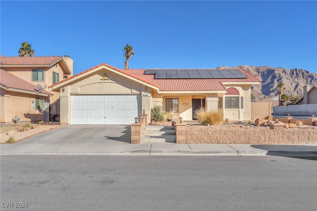 view of front of home featuring a garage, a mountain view, and solar panels