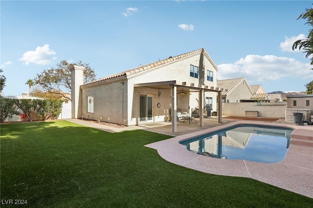 rear view of house featuring ceiling fan, a yard, a fenced in pool, and a patio