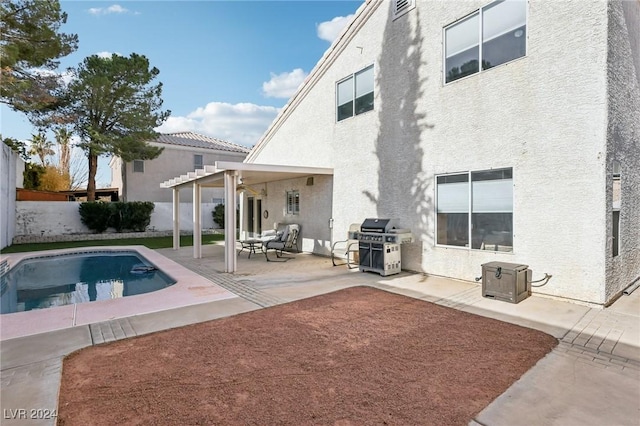 rear view of property featuring a fenced in pool, a pergola, and a patio area