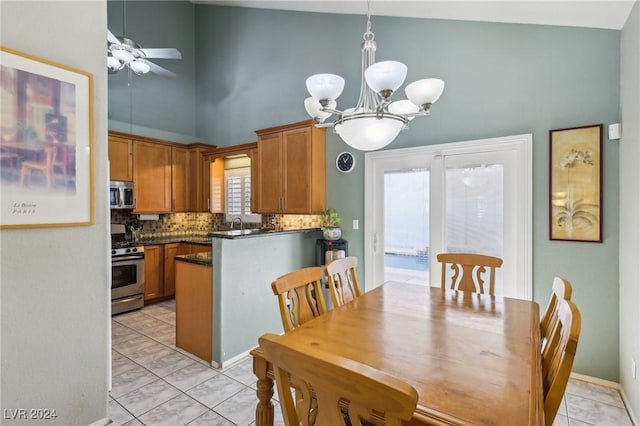 dining space with a towering ceiling and ceiling fan with notable chandelier