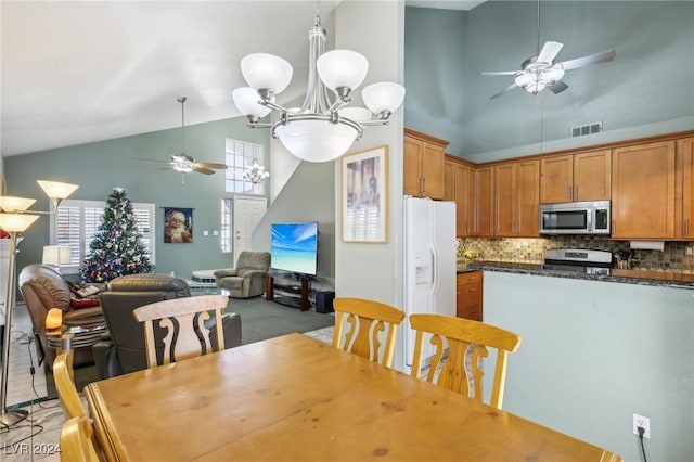 dining room with ceiling fan with notable chandelier and high vaulted ceiling