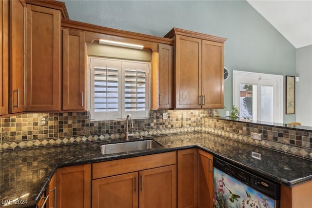 kitchen featuring sink, vaulted ceiling, dark stone countertops, dishwasher, and decorative backsplash