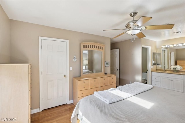 bedroom featuring ensuite bathroom, sink, and light hardwood / wood-style flooring