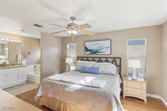 bedroom featuring sink, light hardwood / wood-style floors, ceiling fan, and ensuite bathroom