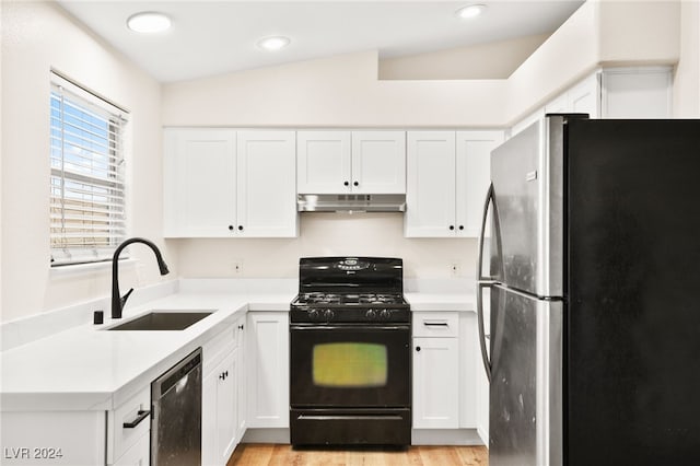 kitchen with black appliances, white cabinets, sink, and vaulted ceiling