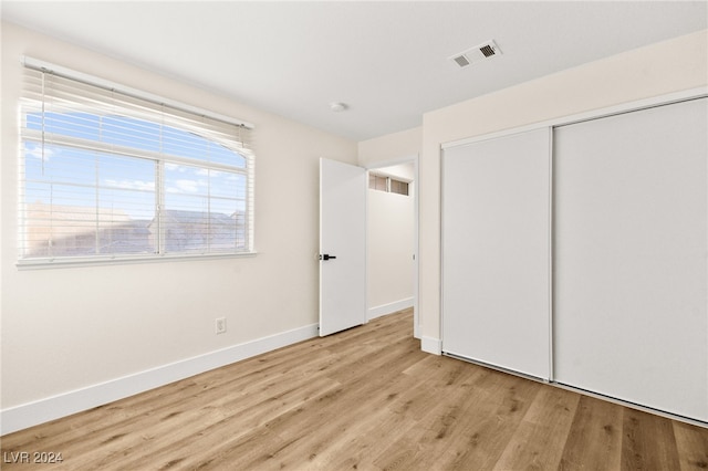 unfurnished bedroom with a closet and light wood-type flooring