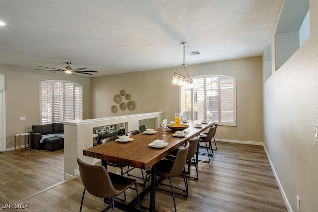 dining room with ceiling fan with notable chandelier and hardwood / wood-style flooring