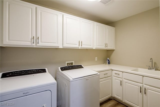 laundry area with cabinets, dark hardwood / wood-style flooring, washing machine and dryer, and sink