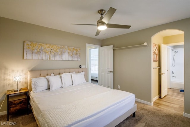 carpeted bedroom with ensuite bath and ceiling fan