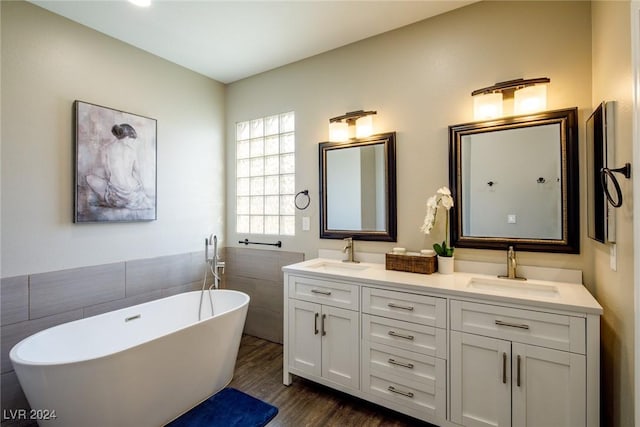 bathroom featuring hardwood / wood-style floors, vanity, a tub to relax in, and tile walls