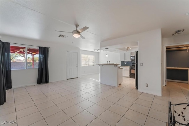 unfurnished living room with ceiling fan, light tile patterned flooring, and a healthy amount of sunlight