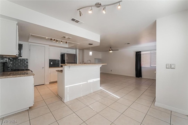 kitchen with stainless steel fridge, tasteful backsplash, light stone counters, ceiling fan, and white cabinets