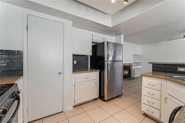 kitchen with decorative backsplash, light tile patterned flooring, white cabinetry, and appliances with stainless steel finishes