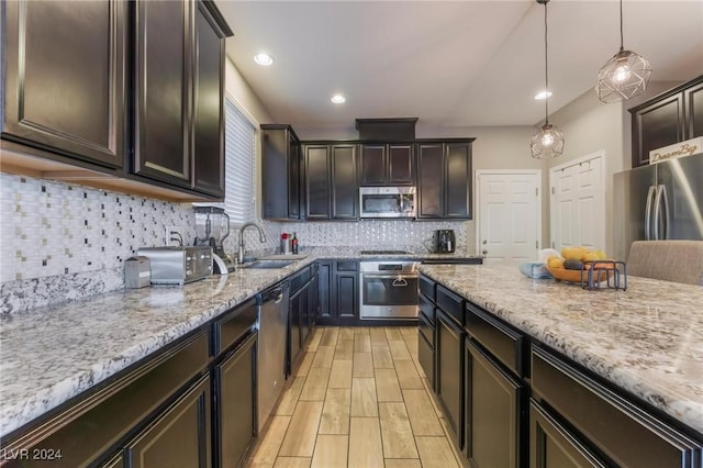 kitchen featuring dark brown cabinetry, sink, hanging light fixtures, decorative backsplash, and appliances with stainless steel finishes