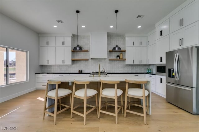 kitchen featuring pendant lighting, a center island with sink, open shelves, appliances with stainless steel finishes, and white cabinetry