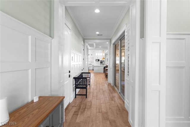 corridor with light hardwood / wood-style floors and crown molding