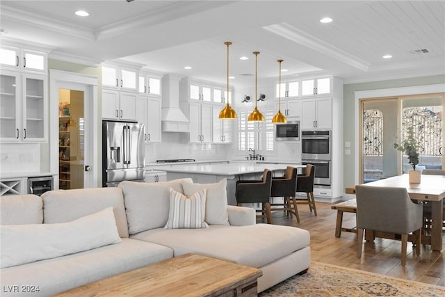 living room featuring light hardwood / wood-style flooring, beverage cooler, ornamental molding, and sink