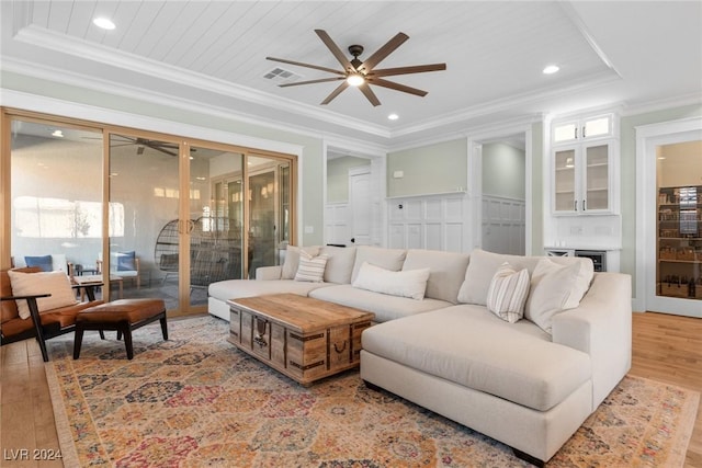 living room featuring a raised ceiling, light hardwood / wood-style floors, and ornamental molding