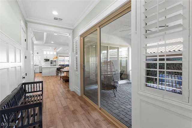 hallway with a healthy amount of sunlight, hardwood / wood-style flooring, and ornamental molding