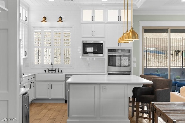 kitchen with sink, hanging light fixtures, decorative backsplash, appliances with stainless steel finishes, and white cabinetry