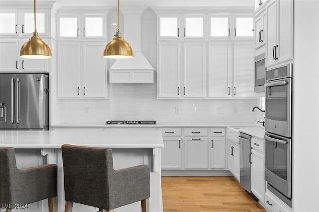 kitchen featuring white cabinetry, sink, pendant lighting, appliances with stainless steel finishes, and light wood-type flooring