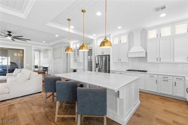 kitchen with stainless steel fridge with ice dispenser, decorative light fixtures, white cabinets, custom exhaust hood, and light wood-type flooring