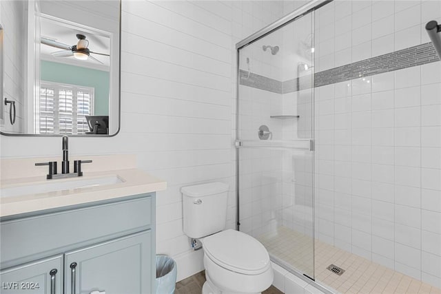 bathroom featuring vanity, a shower with door, toilet, and ceiling fan