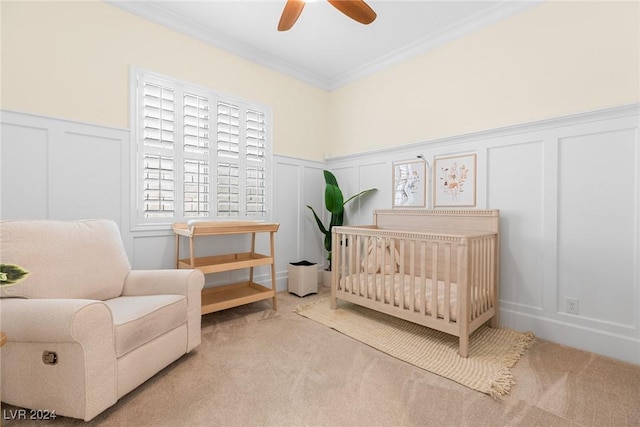 carpeted bedroom with ceiling fan, crown molding, and a nursery area