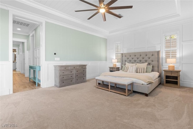 carpeted bedroom with a raised ceiling, ceiling fan, and crown molding