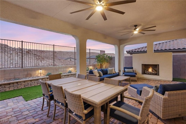 patio terrace at dusk featuring an outdoor living space with a fireplace