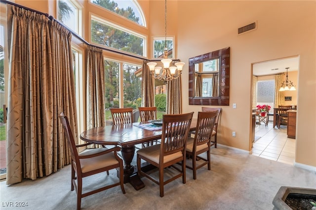 dining area featuring a towering ceiling, light colored carpet, and a chandelier