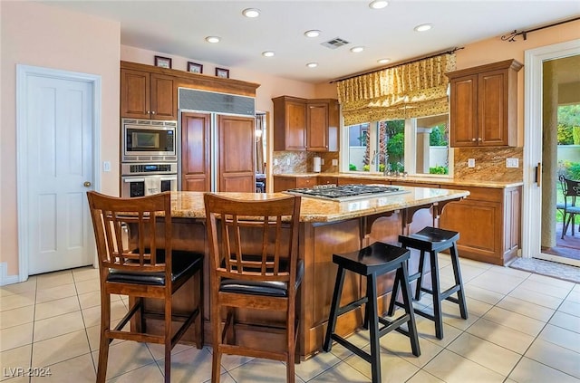 kitchen with a center island, built in appliances, and light stone counters