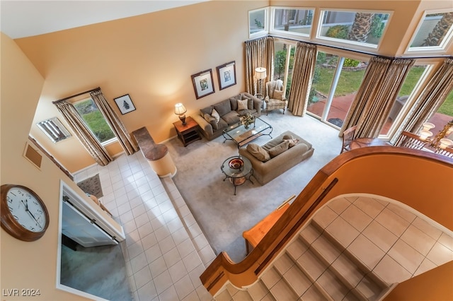 living room featuring light tile patterned floors, a healthy amount of sunlight, and a high ceiling