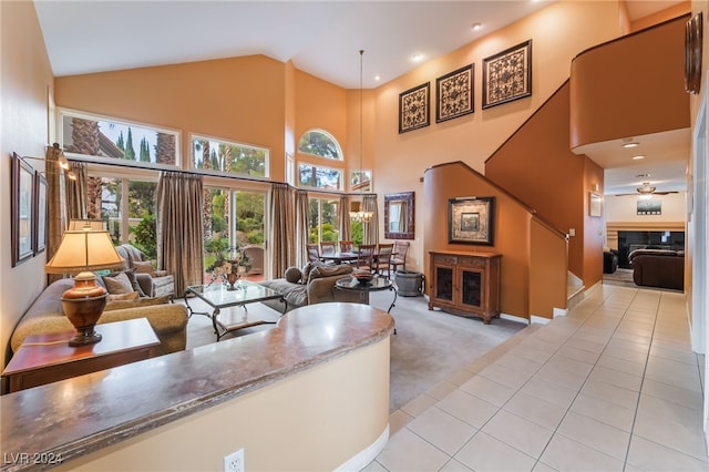 carpeted living room featuring ceiling fan and a towering ceiling