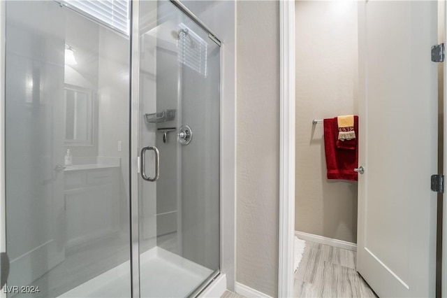 full bath with a shower stall, wood finished floors, and baseboards