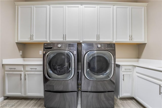 washroom with washer and dryer, cabinets, and light wood-type flooring