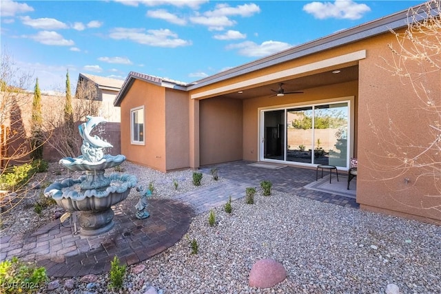 rear view of house with stucco siding, fence, a ceiling fan, and a patio area