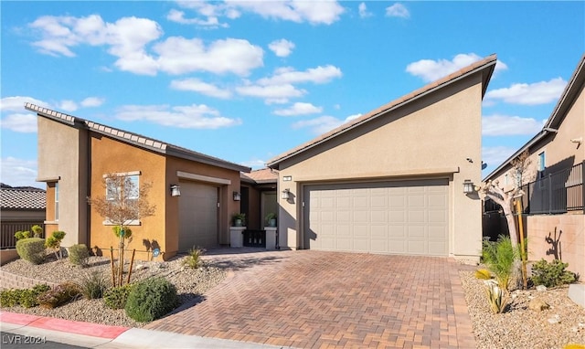 mid-century modern home with decorative driveway, an attached garage, fence, and stucco siding